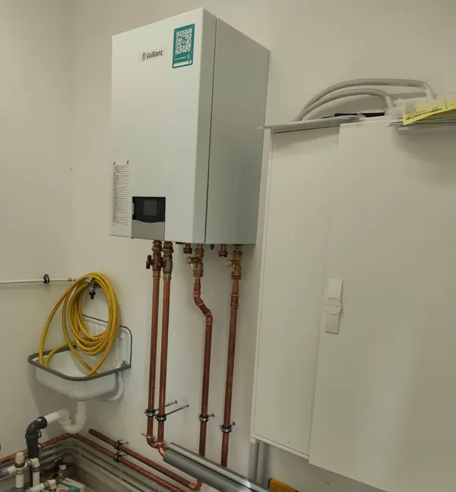 Wandhängende Hydraulikstation einer Luft-Wasser-Wärmepumpe mit neu verlegten Kupferleitungen und Absperrungen im Technikraum