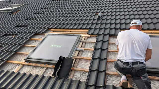 Monteur setzt ein neues Dachfenster in das geöffnete Steildach ein