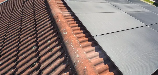 Photovoltaikmodule neben dem First eines Ziegeldachs, Detailansicht der Anlage